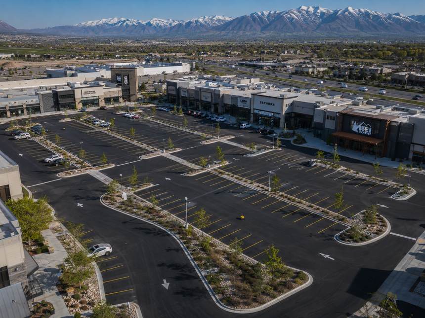 Aerial of a retail center lot with new striping, snow-capped mountains behind